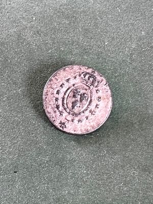 une pièce d'argent sur laquelle figure une couronne, posée sur un fond vert