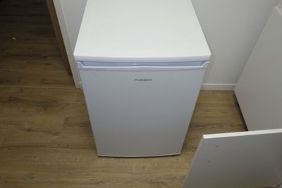 une photo d'un petit réfrigérateur blanc dans un coin d'une pièce