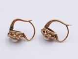 two pairs of gold earrings with pearls on them on a white surface