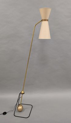 a brass floor lamp with a white shade on top of it