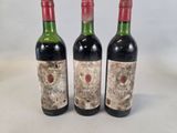 trois bouteilles de vin rouge sont posées sur une surface blanche