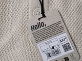 the back of a white sweater with a tag attached to it