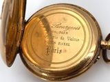 an old gold pocket watch with a chain on a white surface