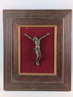 un crucifix en bronze dans un cadre en bois recouvert de velours rouge