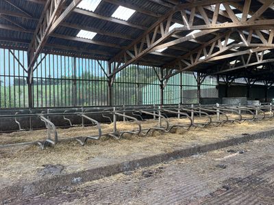des rangées de foin dans une grange remplie de bancs en bois et de rampes métalliques