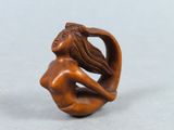 statue d'une femme assise sur une vague, les cheveux au vent