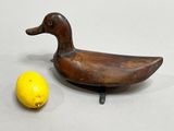 a wooden duck sitting next to a lemon on a table