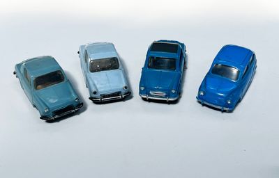 quatre petites voitures sont alignées sur une surface blanche