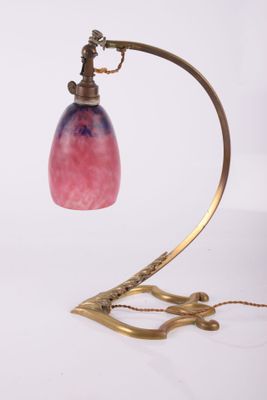brass table lamp with a pink glass shade on a curved metal stand