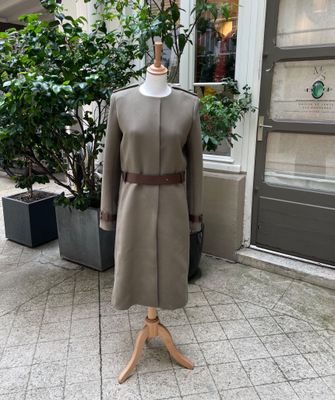 un mannequin devant un immeuble, avec un arbre en arrière-plan