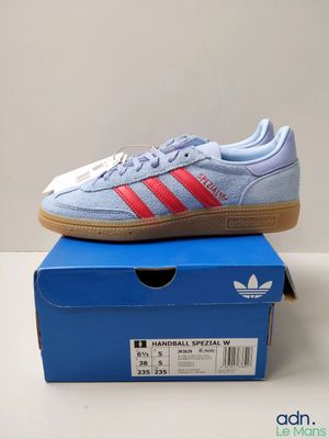 une paire de baskets Adidas posée sur une boîte bleue