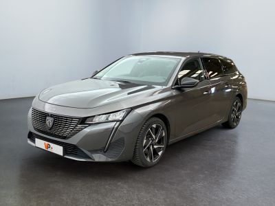 La voiture grise est garée dans une pièce blanche au sol noir.