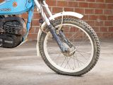 a blue dirt bike parked in front of a brick wall