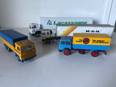 trois camions miniatures posés les uns à côté des autres sur une table