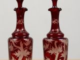 two red glass vases sitting on top of a wooden table