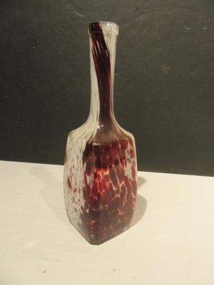 un vase rouge et blanc posé sur une table blanche