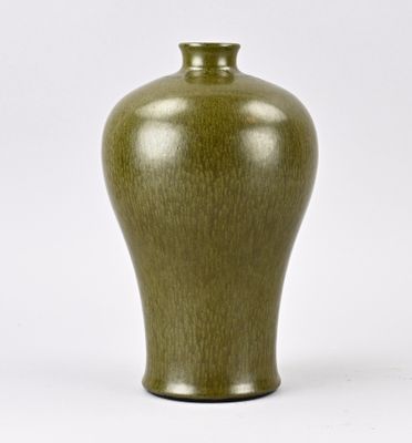 un vase vert posé sur une surface blanche