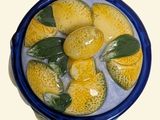 a blue bowl filled with lemons on a white surface