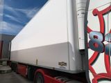 un semi-remorque blanc avec un logo rouge et bleu sur le côté