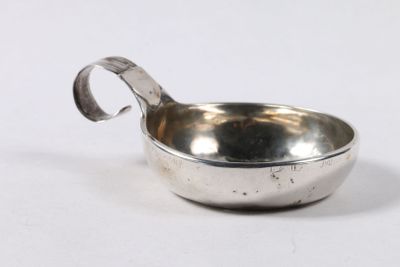 un petit bol en argent avec une poignée sur une surface blanche