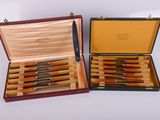 two wooden boxes with knives in them on a white surface