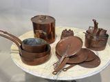 un grand nombre de casseroles et de poêles en cuivre posées sur une table