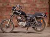 a black motorcycle parked in front of a brick wall