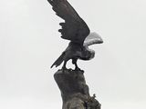 statue of an eagle perched on a tree stump on a white background