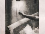 black and white photograph of a person holding a lamp above a bed