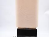 the lamp is on a black base with a beige shade