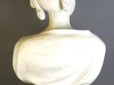 marble bust of a woman with braided hair on a stand