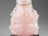une tabatière en jade rose ornée de figures sculptées, posée sur un socle