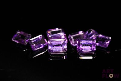 three pieces of purple glass are sitting on a black surface