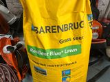 a bag of grass seed next to a pair of lawn mowers