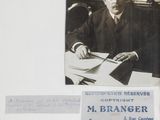 a black and white photo of a man in a suit sitting at a desk