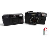 two cameras sitting next to each other on a white surface