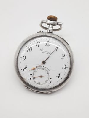 une montre de poche en argent posée sur une surface blanche