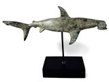 statue of a shark on a black stand on a white background