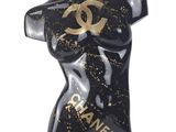 black and gold chanel statue of a woman with a chanel logo on her chest