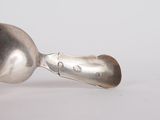 a silver spoon with a spoon handle on a white surface