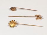 three gold pins and a pin with a flower on them