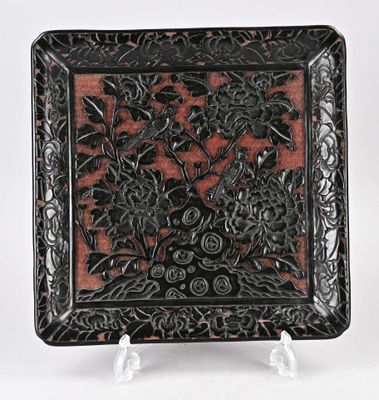 une assiette noire et rouge décorée de fleurs