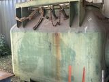 un char qui se trouve dans l'herbe, à côté d'un bâtiment