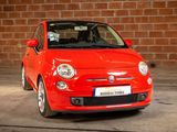 a small red car parked in front of a brick wall
