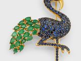 a close up of a bird brooch with blue and green stones