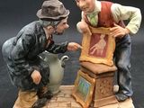 a figurine of two men sitting on top of a box