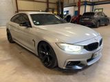 the bmw m4 is parked in a garage with other cars in the background