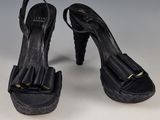 une paire de chaussures à talons hauts en cuir noir, ornées de volants au niveau des orteils