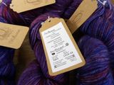 several skeins of purple and blue yarn with labels on them