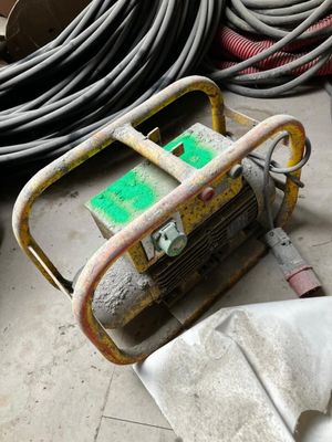 un petit générateur portable posé par terre à côté d'un tas de tuyaux